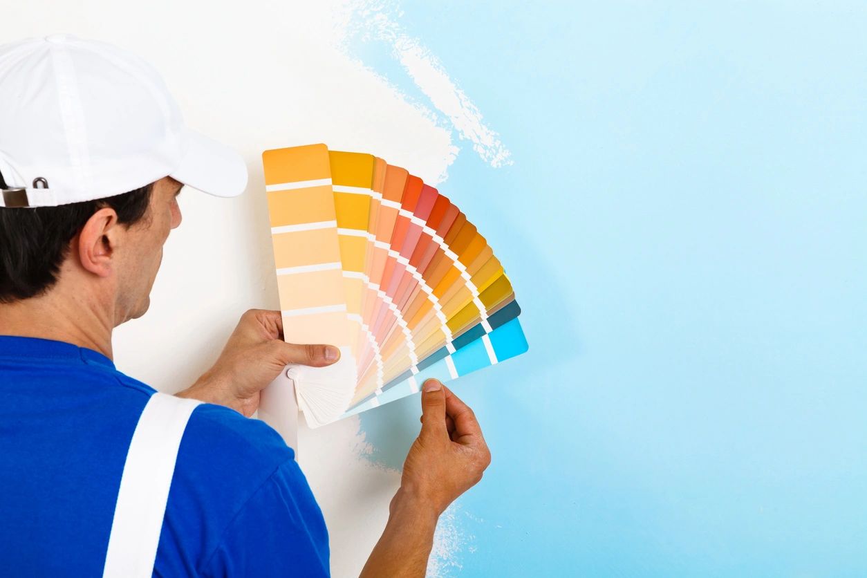 A person holding up a color swatch to paint the wall.