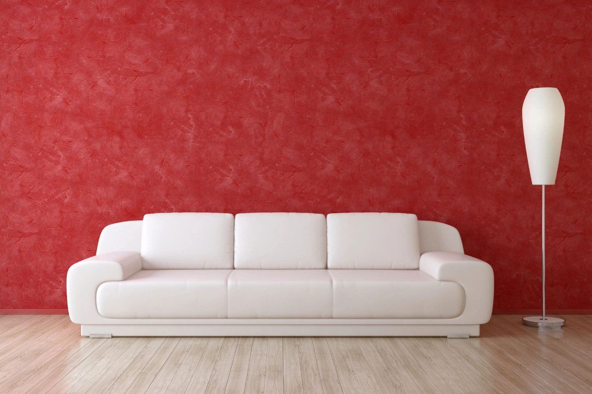 A white couch in front of a red wall.