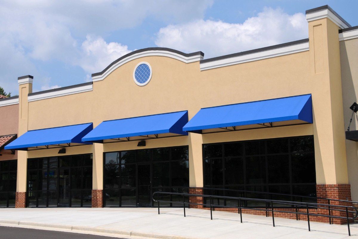 A store front with blue awnings and a white building.