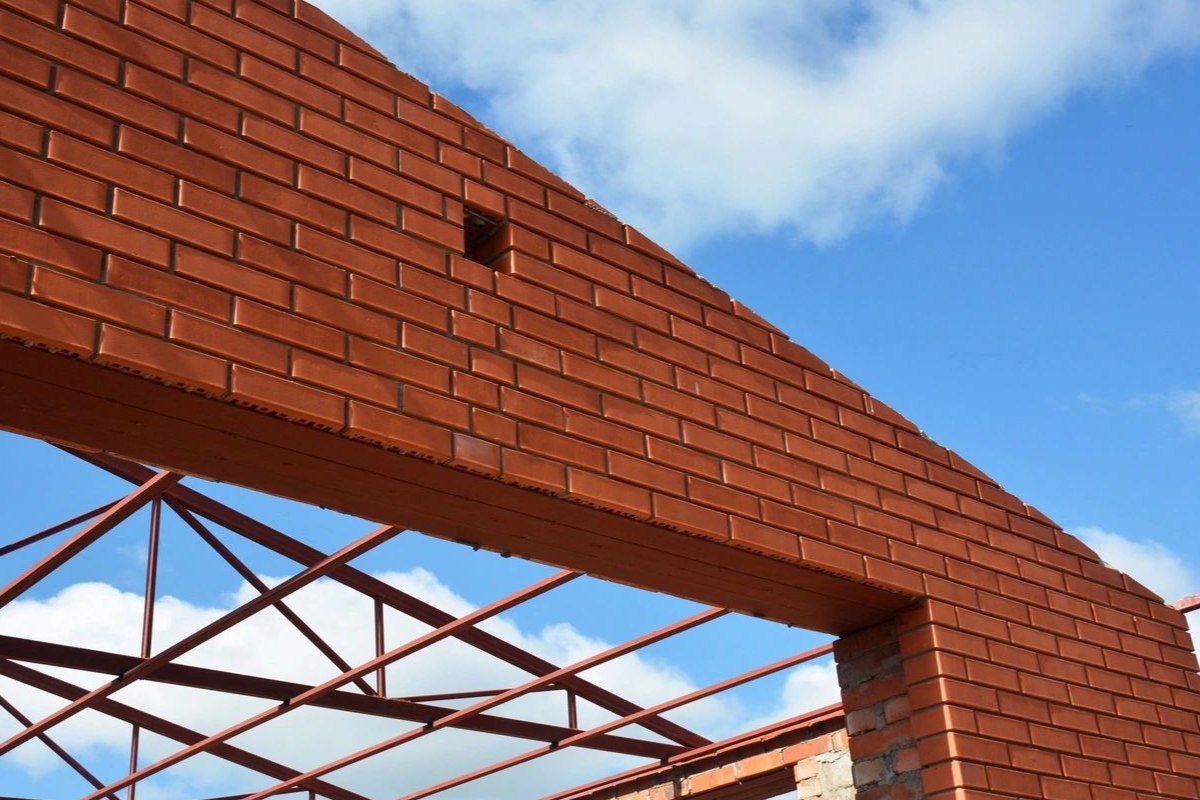 A brick wall with a metal roof and sky background