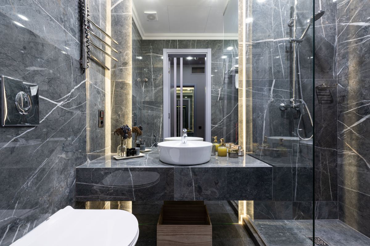 A bathroom with marble walls and floors, a sink and toilet.