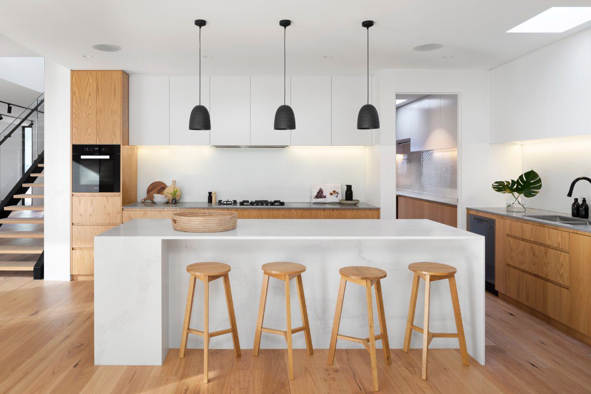 A kitchen with four stools and three hanging lights.